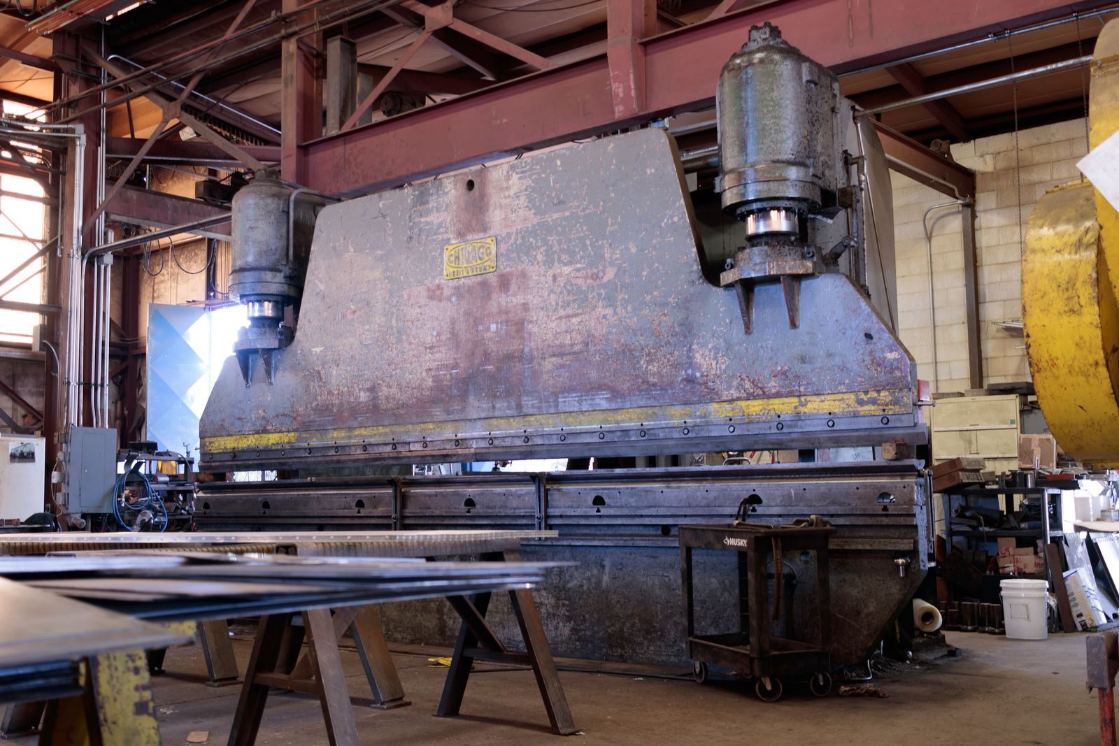 Press brake forming a sheet metal component in a fabrication workshop.