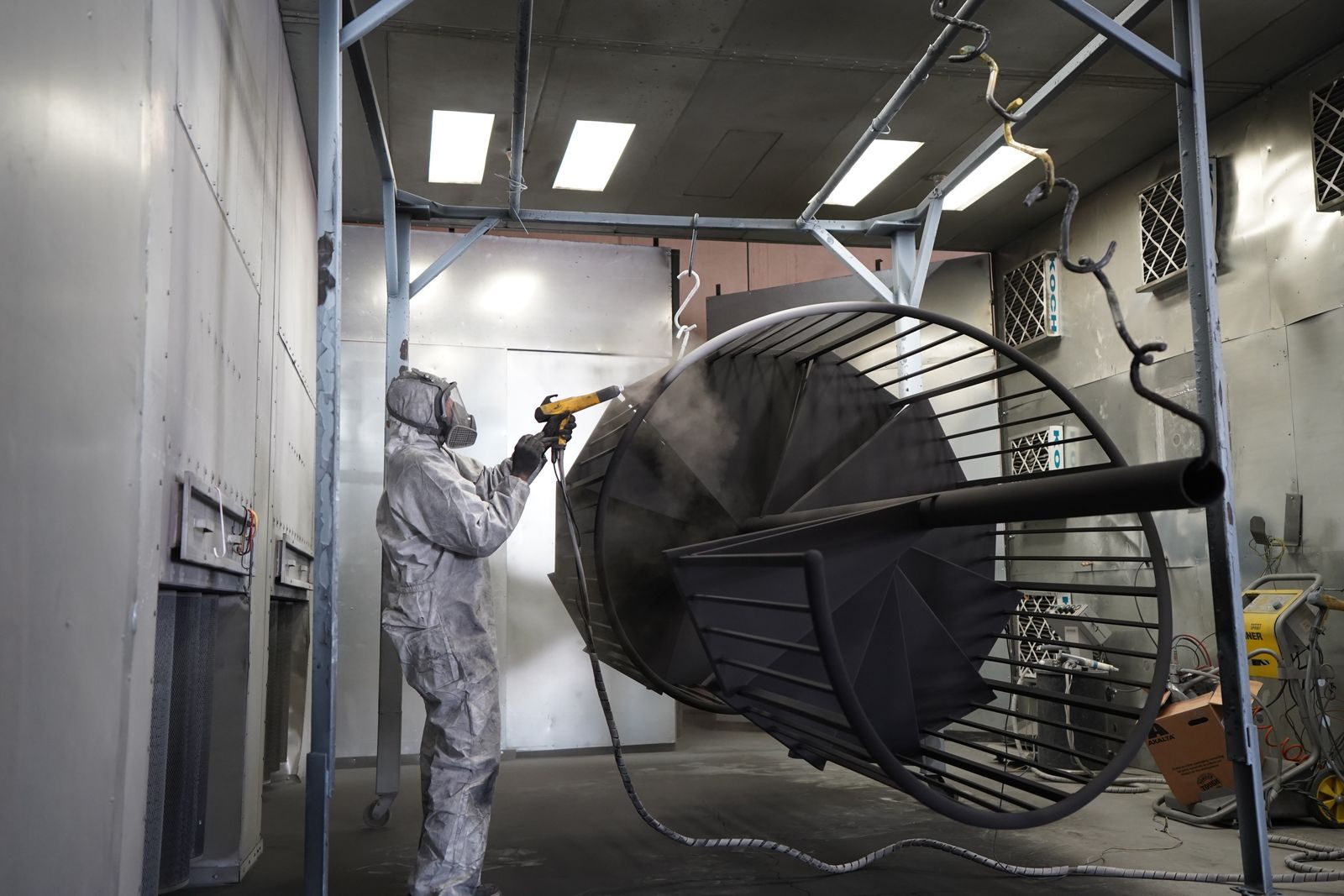 Powder coating being applied to metal parts on a production line.