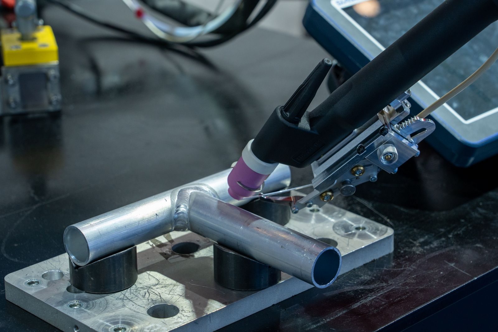 Laser welding head directing a beam onto a sheet metal joint.