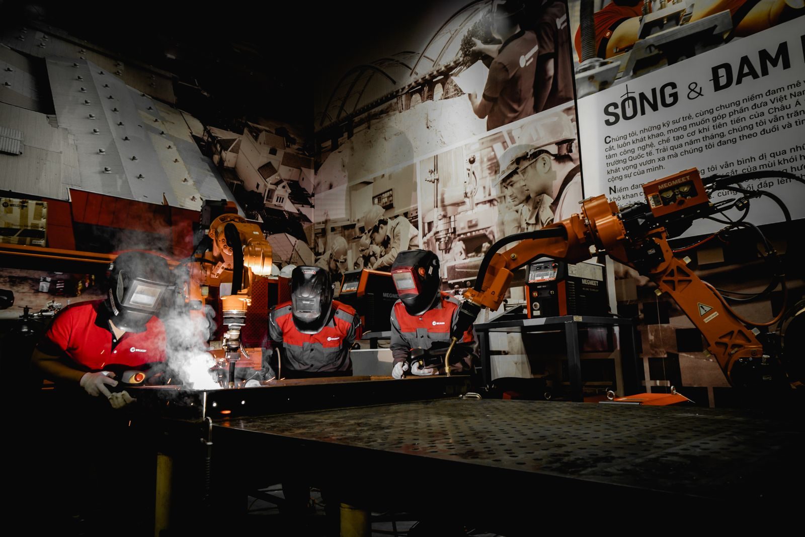 Industrial robotic welding cell with an articulated arm over a workpiece.
