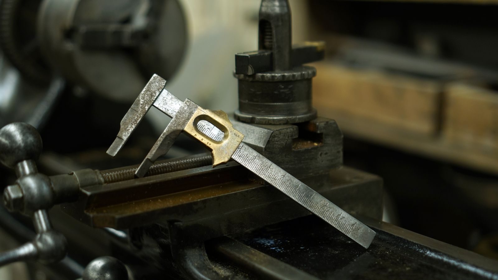 Digital caliper measuring a machined metal component on a workbench.